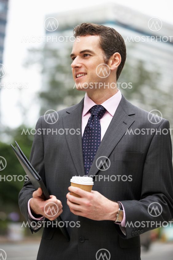 Businessman Walking Along Street Holding Takeaway Coffee