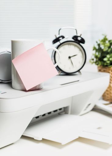 Coffee mug with sticky note beside an alarm clock and a...