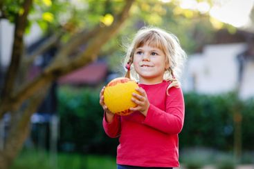 Little adorable toddler girl playing with ball outdoors....