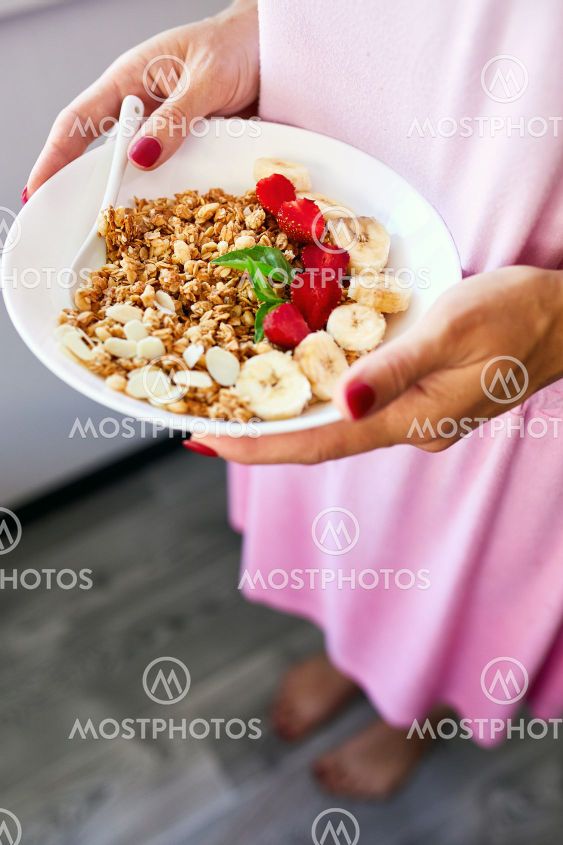 Woman eating healthy breakfast bowl, hold in hand