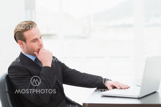 Focused businessman in suit using laptop