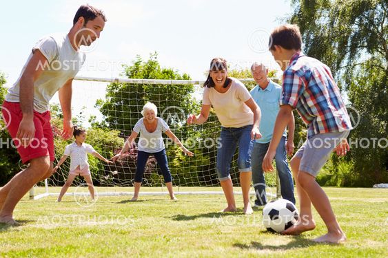 Multi Generation Playing Football In Garden Together