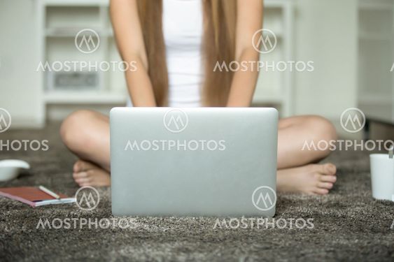 Female sitting legs crossed at the floor, laptop in front