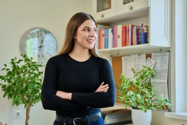 Confident young woman with crossed arms in home interior