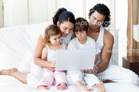 Family using a laptop on the bed