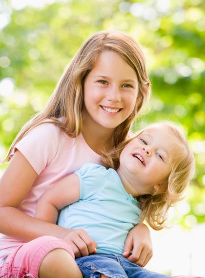 Two sisters sitting outdoors smiling