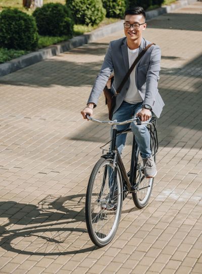 handsome smiling asian man cycling on bike in city