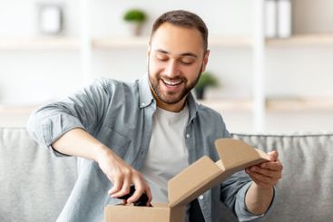 Happy Caucasian man receiving package, unboxing parcel,...