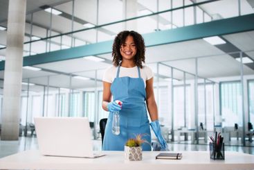 Portrait Of Happy Female Worker Cleaning Computer Desk...