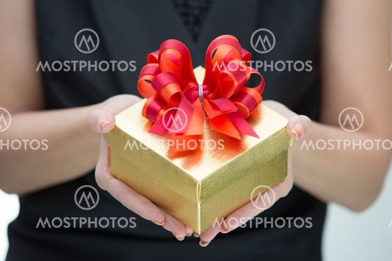 Golden gift box with red and orange satin bow on hand