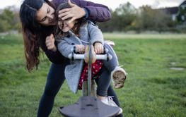 Happy mother playfully covers the eyes of her little...