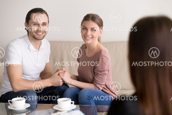 Cheerful young family couple on consultation. Holding hands and