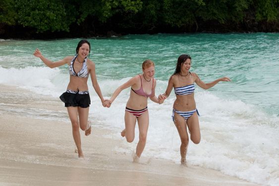 Three girls run on the beach