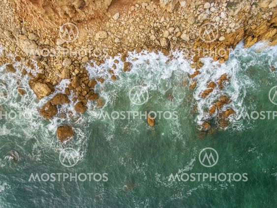 Aerial. Waves beat against the shore, the view from the...