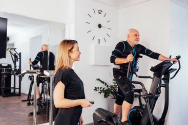 Young smiling trainer is doing electrical muscle...