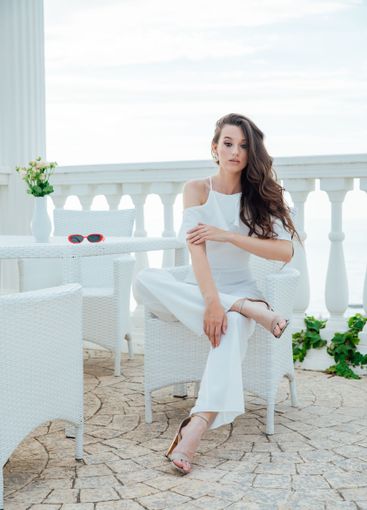 fashionable brunette woman in white suit sitting at...