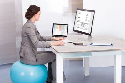 Woman Sitting On Pilates Ball Using Computer
