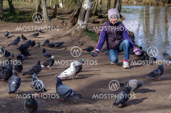 Child playing with doves in the city street. young girl feeding pigeons.