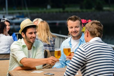 Three male friends drinking beer outdoor terrace
