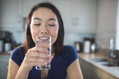 Young woman drinking a glass of water in kitchen