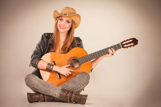 The beautiful girl in a cowboy's hat and acoustic guitar.