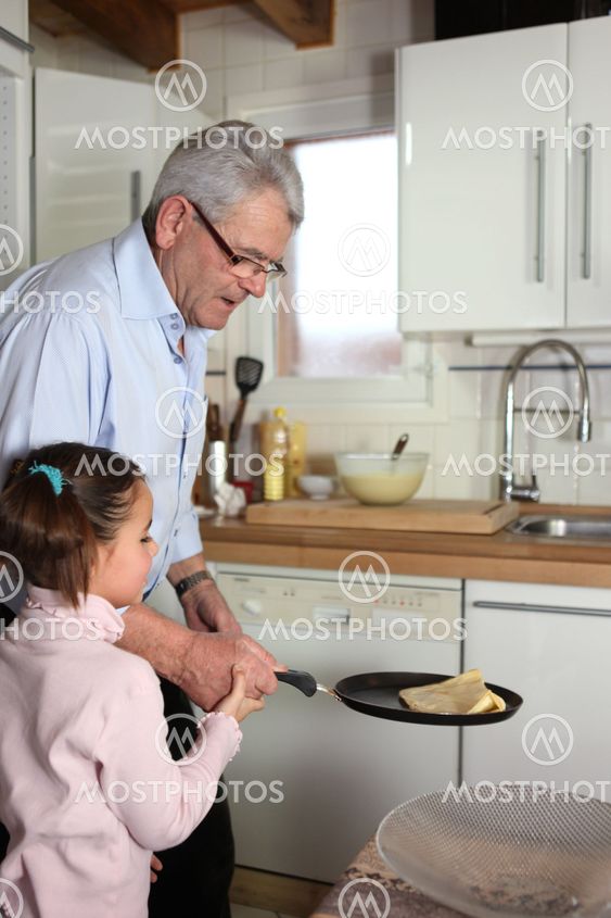 Little girl tossing pancakes with her granddad