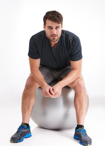 Man, exercise ball and sitting in studio with break for...