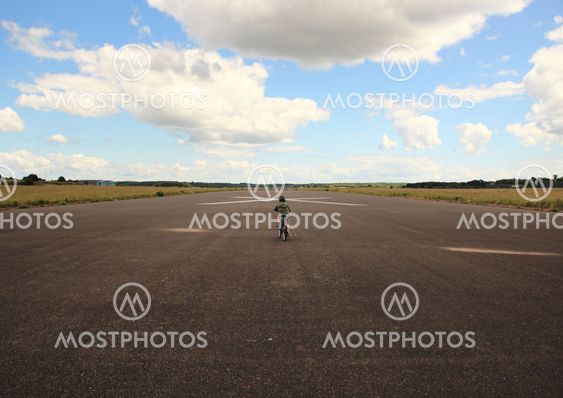 Biking child with helmet on airplane runway