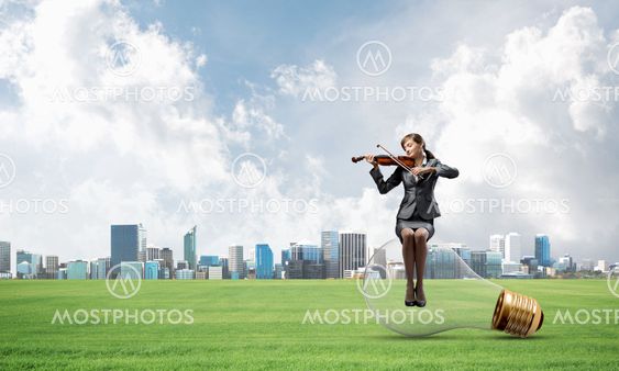 Young woman with violin sitting on big light bulb
