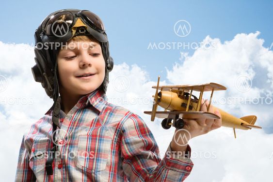 Boy in helmet pilot playing with a toy airplane