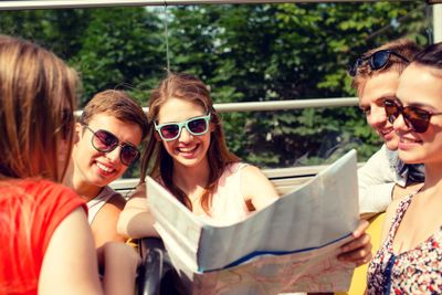 group of smiling friends traveling by tour bus