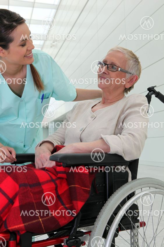Nurse talking to an elderly lady in a wheelchair