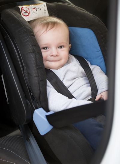 Cute smiling baby boy sitting in car child seat