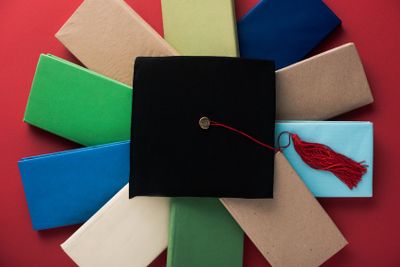 Top view of black graduation cap with tassel on books on...