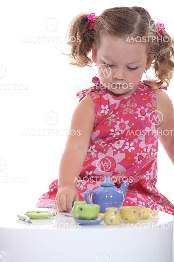 Little girl playing with model teapot and mugs