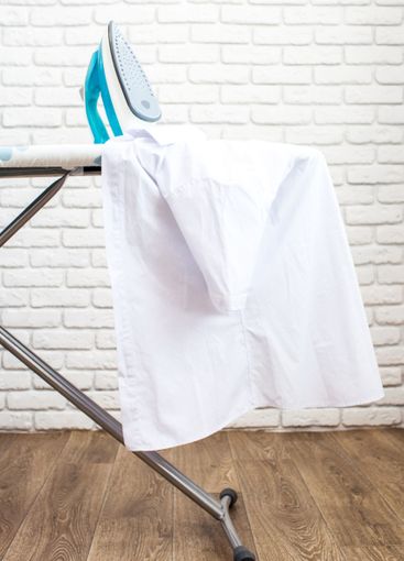 Iron on ironing board on light home interior background