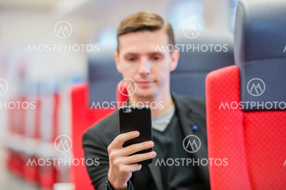 Young man traveling by train. Tourist writing a message...