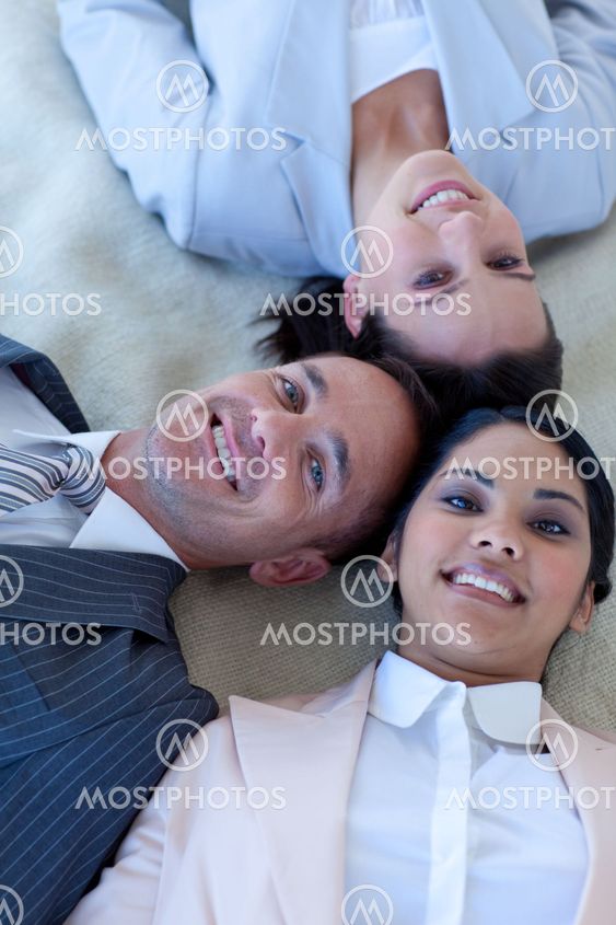 Business team on floor with heads together smiling