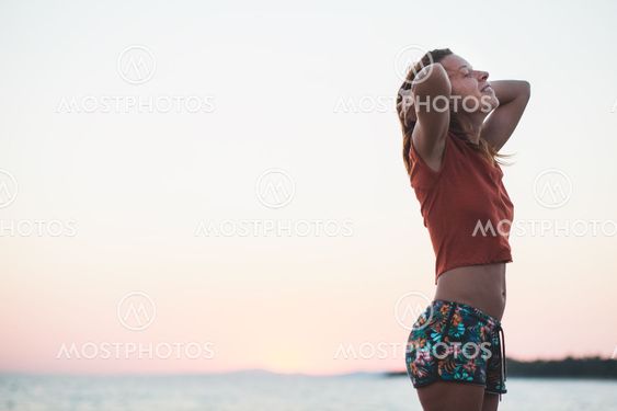 Young woman enjoying sunset by the sea