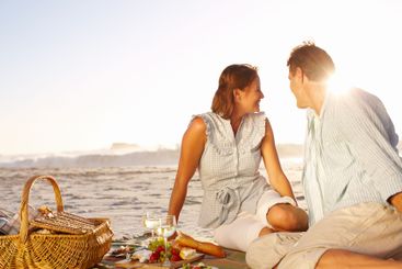 Seaside, couple and happiness on picnic with wine glass...