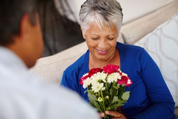 Bouquet, smile and flowers with old couple in living...