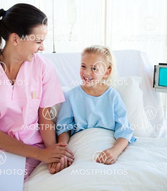 Smiling little girl sitting on a hospital bed with her doctor