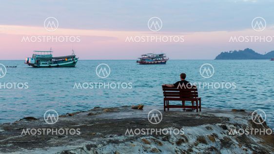 Lonely man on the evening shore of the sea.