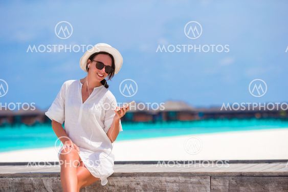 Young beautiful woman listening to music on wooden bridge