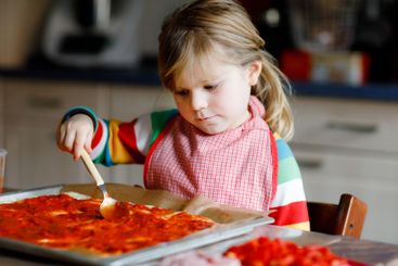 Adorable little toddler girl making italian pizza at...