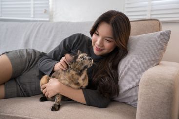 A woman lying on a couch, lovingly cuddling with her...