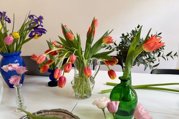 Mixed flower arrangements in colorful vases on white...