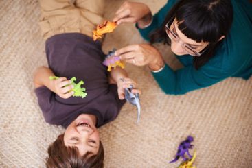 Woman, kid and toy with dinosaur, carpet and play for...