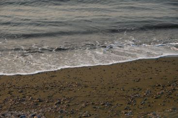Waves gently lap against the rocky shoreline at dusk in...