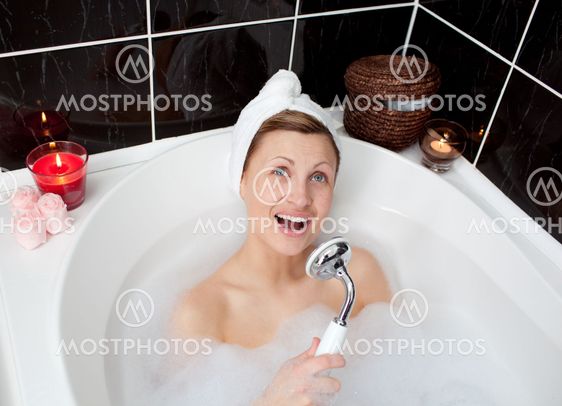 Cheerful young woman singing in a bubble bath